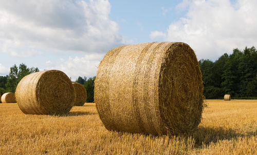 Hay bales on field against sky