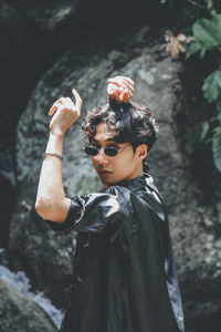 Man wearing sunglasses while standing against rock