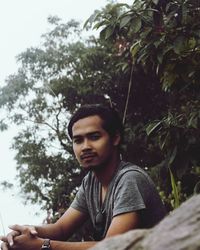 Portrait of young man against trees