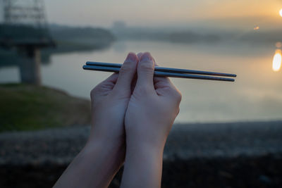 Midsection of woman holding umbrella against sea