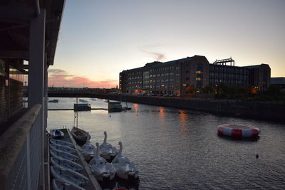 Boats in city against sky at sunset