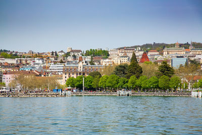 Town by river against clear sky