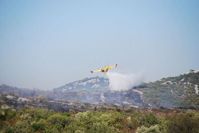 Airplane flying over mountain against sky