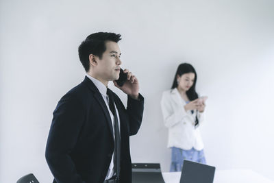 Young man and woman standing against white wall