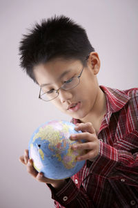 Boy holding globe against white background