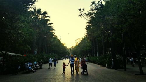 People on road amidst trees against sky