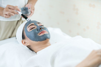 Beautiful woman masking skin in a facial spa shop