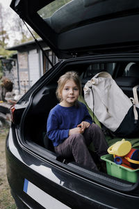 Portrait of girl sitting in electric car trunk