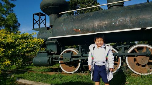 Boy standing by steam train on sunny day