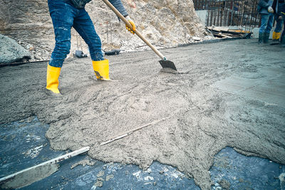 Construction worker uses shovel to spread cement mortar screed. concrete works on construction site