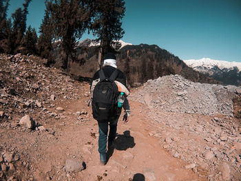 Rear view of man walking on mountain against sky