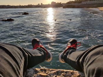Low section of person on shore against sky