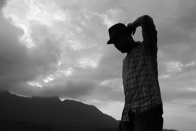 Low angle view of man standing against cloudy sky