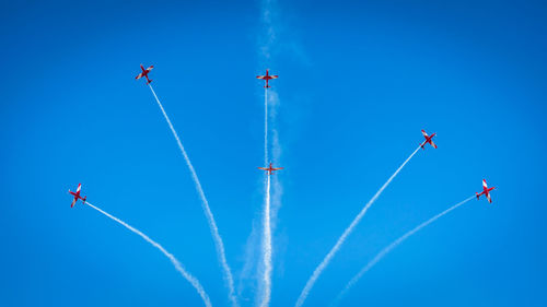 Low angle view of airshow against vapor trails in sky