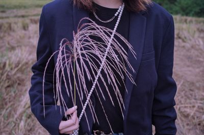 Midsection of man standing with dry crop at field