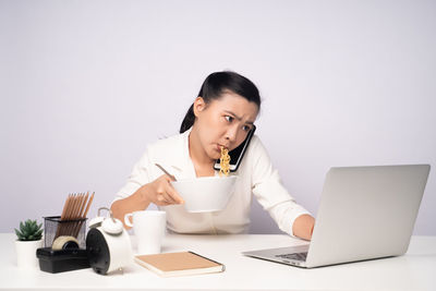 Young woman using mobile phone while sitting on table