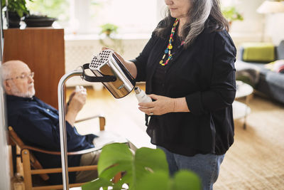 Midsection of senior woman changing bulb at home