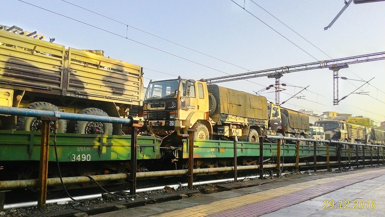 TRAIN AT RAILROAD STATION AGAINST SKY