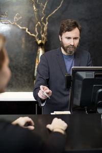 Male receptionist accepting payment through credit card from customer in hotel