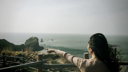 Rear view of woman pointing against sea