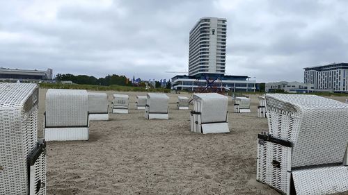 Hooded chairs on beach against buildings in city