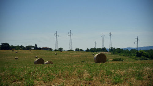 Hay bales on field against clear sky