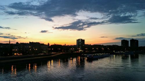 Illuminated buildings in city against sky at sunset