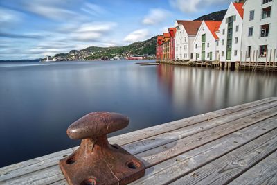 Pier over river by buildings against sky