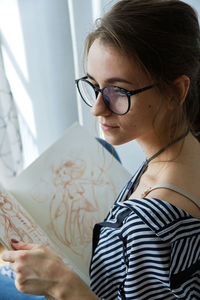 Millennial girl draws fabulous images on paper while sitting at home