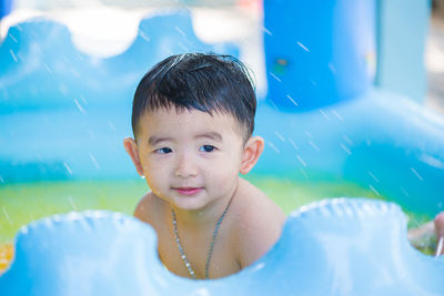 Shirtless boy looking away while enjoying in wading pool