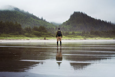 Rear view of man standing on wet beach