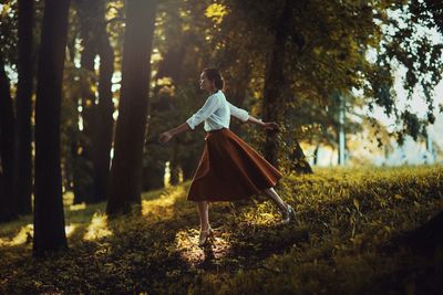 Woman with umbrella on field in forest