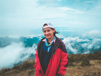 Portrait of smiling woman standing against sky