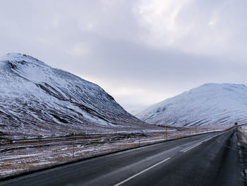 Road by snowcapped mountains against sky