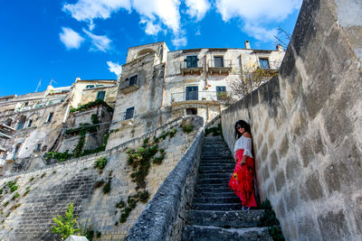 Low angle view of woman amidst buildings against sky