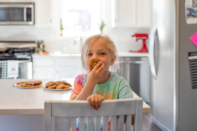 Portrait of cute girl eating cookie at home