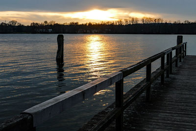 Pier over lake against sky during sunset
