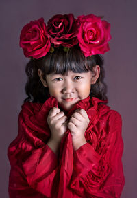 Close-up portrait of smiling girl against red background