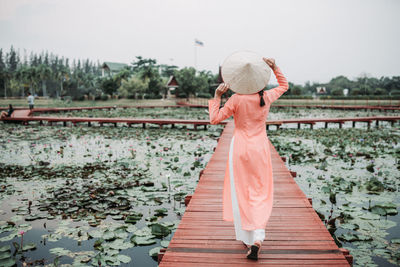 Side view of woman standing by plants against sky