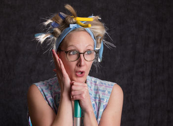 Woman wearing hair curlers against wall