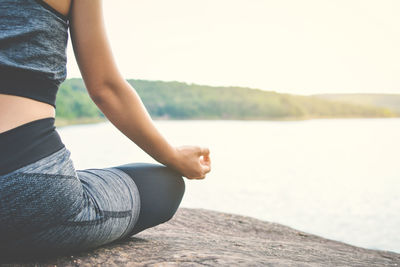 Low section of woman sitting against the sky