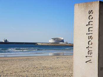Information sign on beach against clear sky