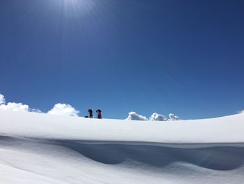 Low angle view of hikers on snow covered mountain against sky