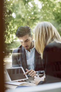 Business colleagues using digital tablet together at sidewalk cafe