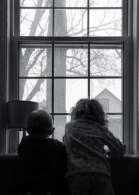 Rear view of girl looking through window