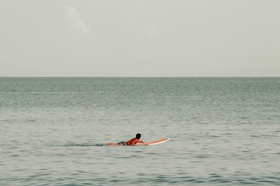 Man surfing in sea against sky