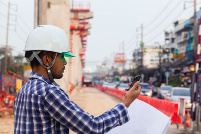 Side view of man holding mobile phone