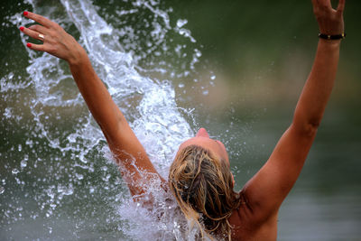 Rear view of young woman splashing water in lake