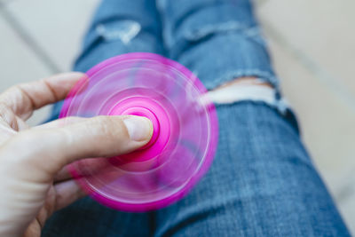 Midsection of person spinning pink fidget spinner