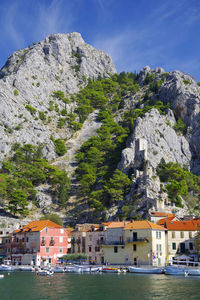 Buildings by mountain against sky